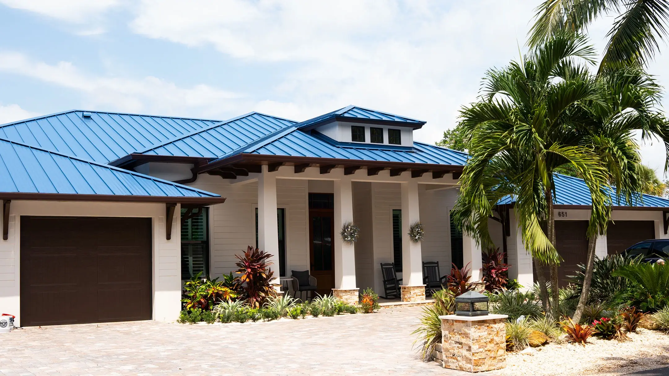 Single-story Florida home with a blue metal hip roof and palms