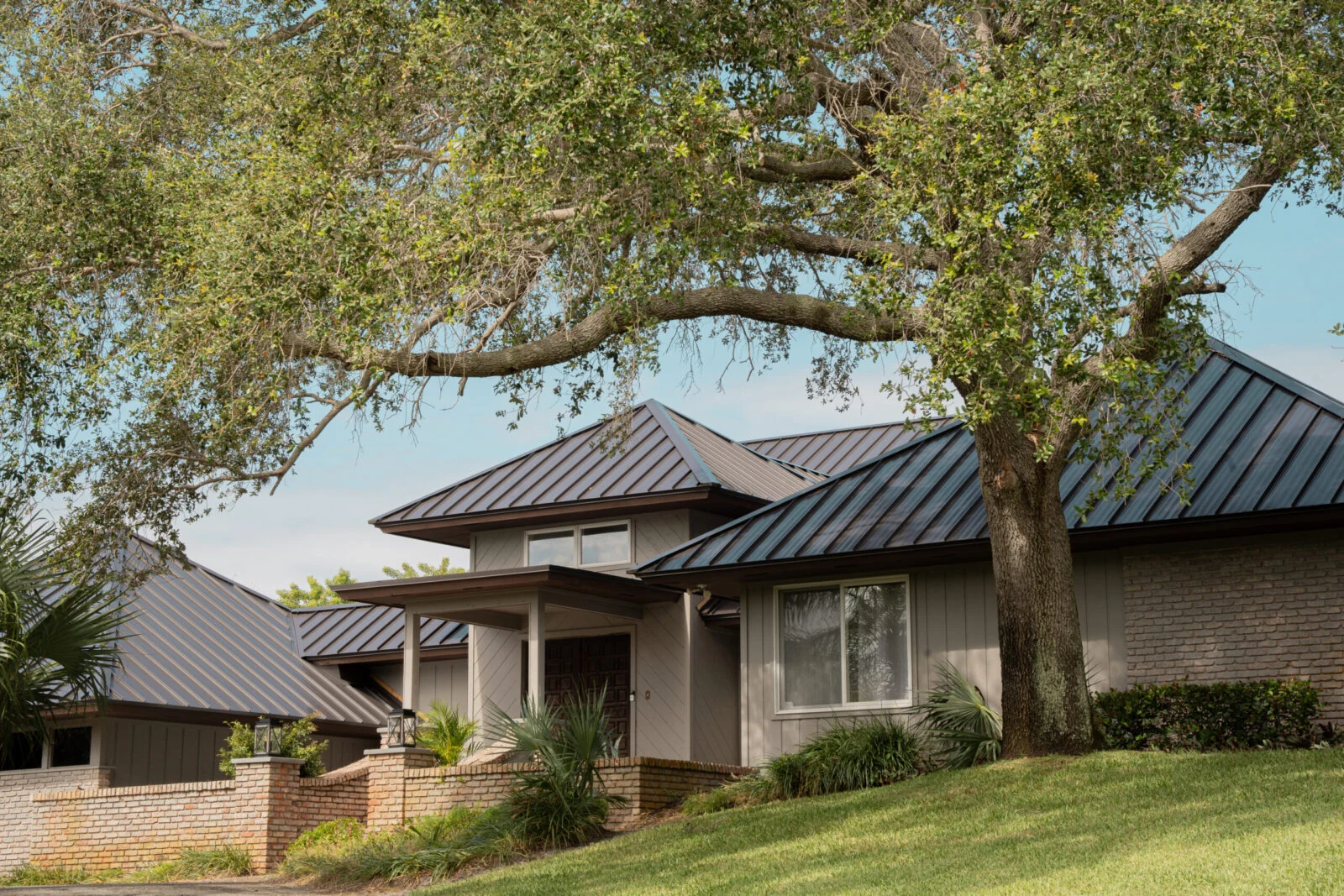 Florida home with a charcoal metal hip roof under an oak