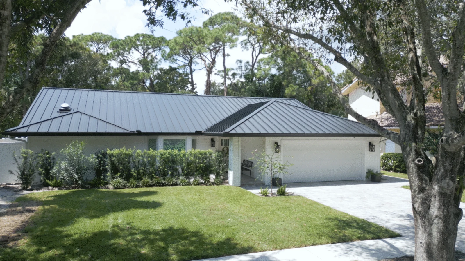 Single-story home with a dark gray metal roof, seen from the street