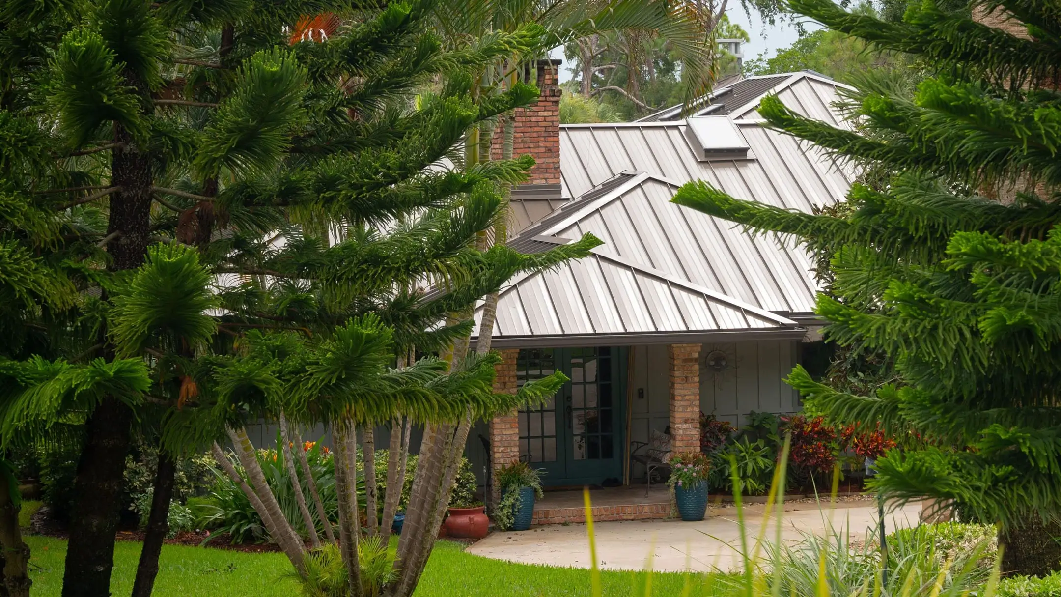 Florida home with a galvalume metal gable roof among tropical trees
