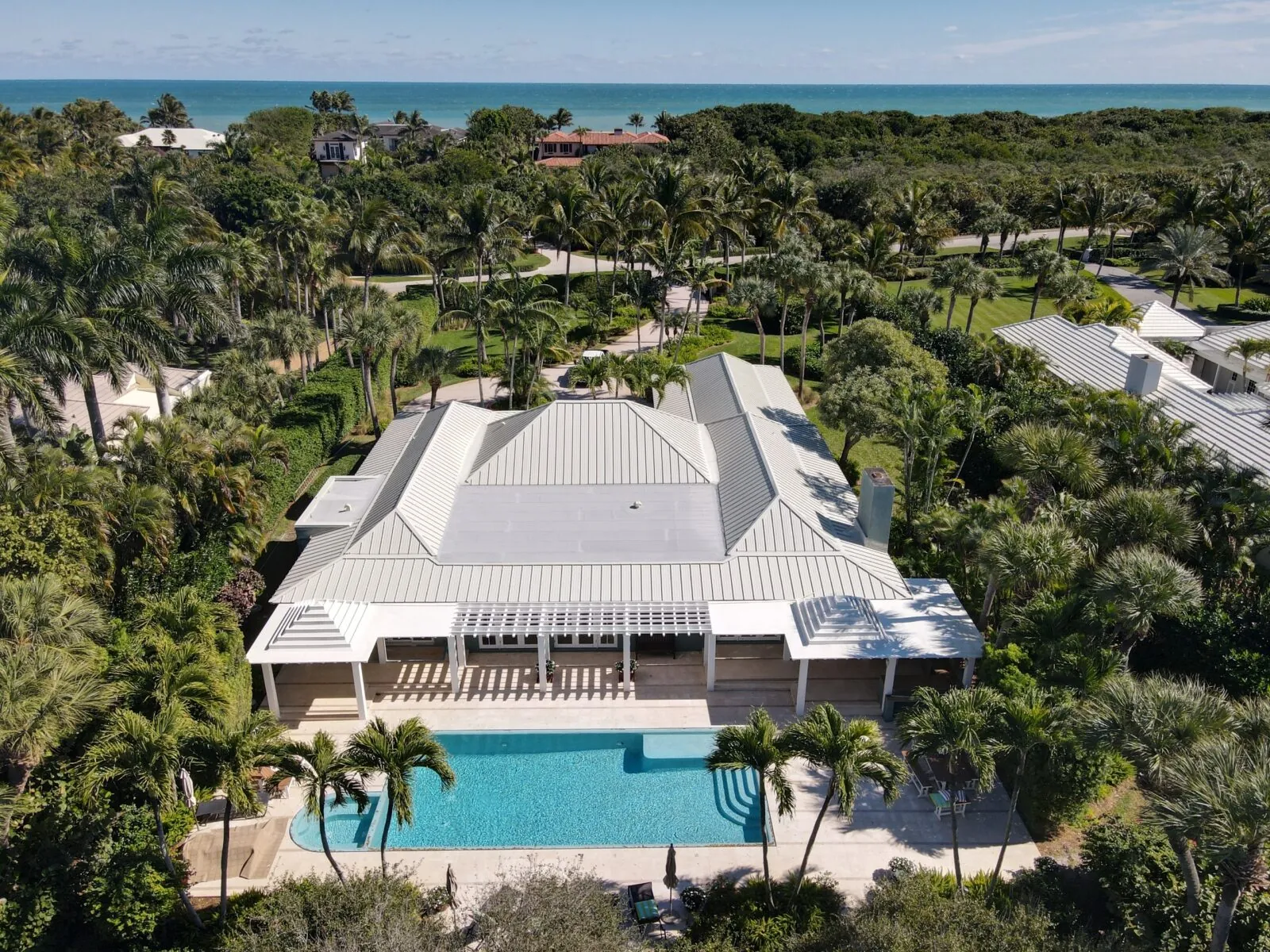 Aerial view of a Florida home with a white metal hip roof and pool