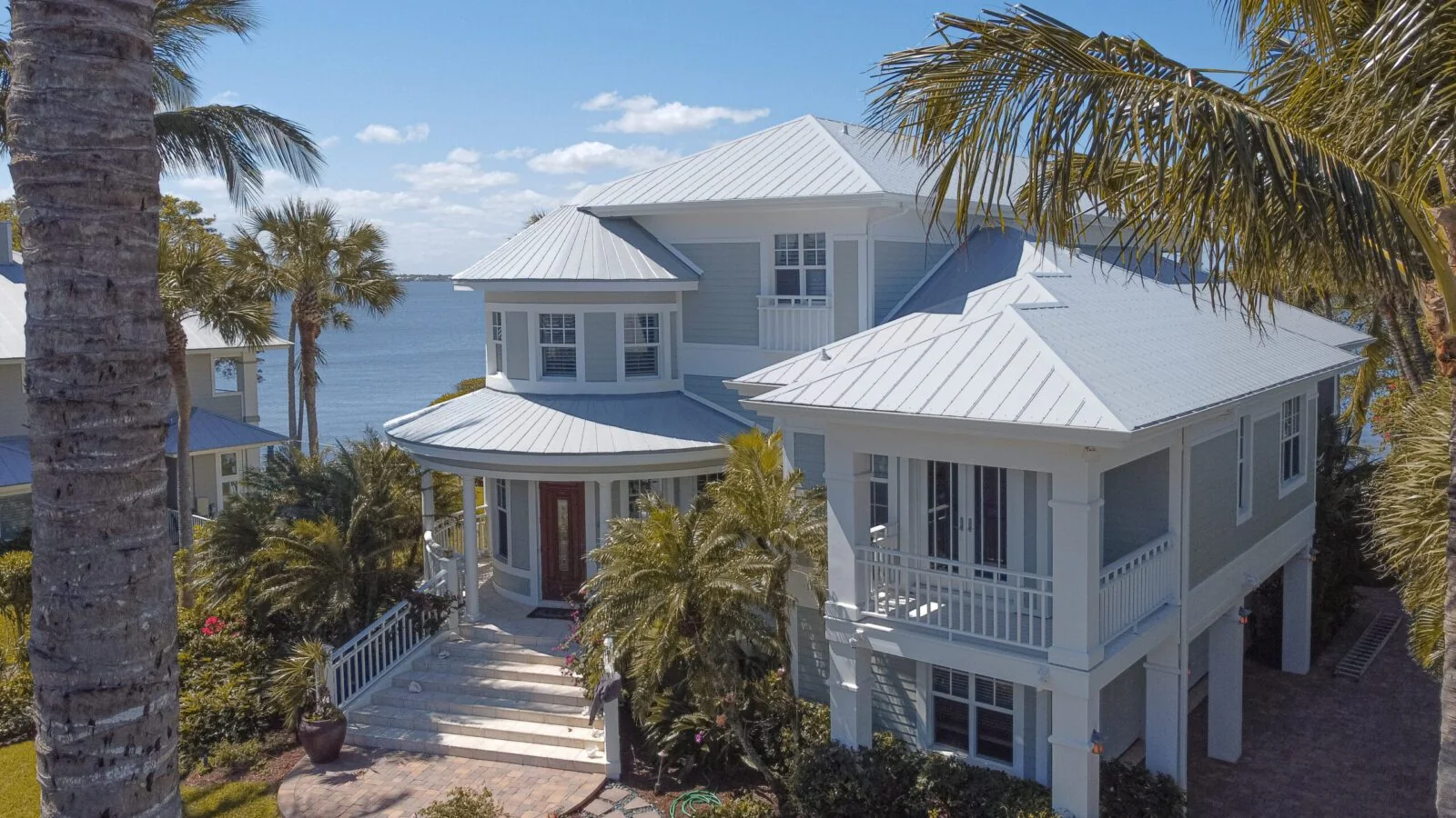 Two-story coastal Florida home with a white metal roof by the bay
