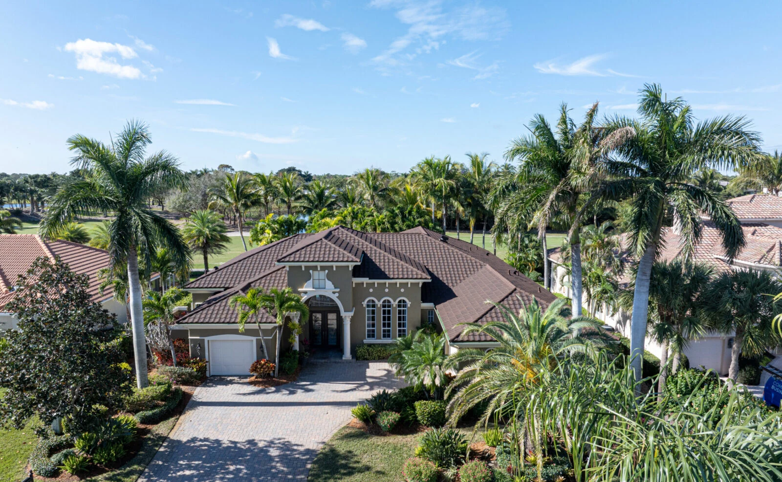 Florida home with a brown tile hip roof among palms